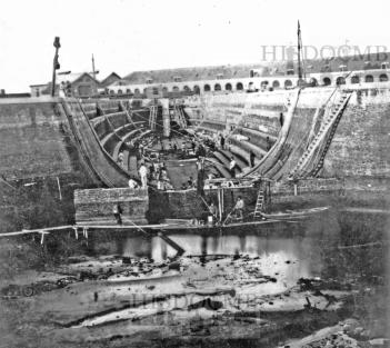 Dok II in aanbouw, gezien vanuit het "Natte DoK". Op de voorgrond het voorlopige afsluitmuurtje, daarachter rechts de waterafpompleidingen voor het afpompen van het dokwater. Bron: HisDocMB 